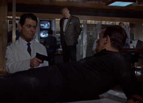 The smug scientist prepares to shoot Bond up with a tranq gun