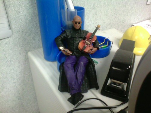 The Morpheus figure sitting in a pen holder holding a violin in his hands.